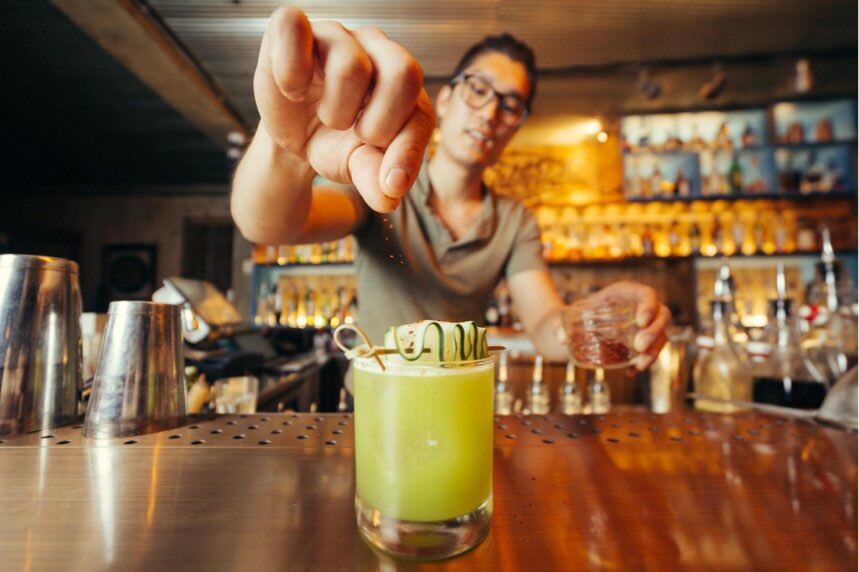Bartender garnishing a bright green cocktail